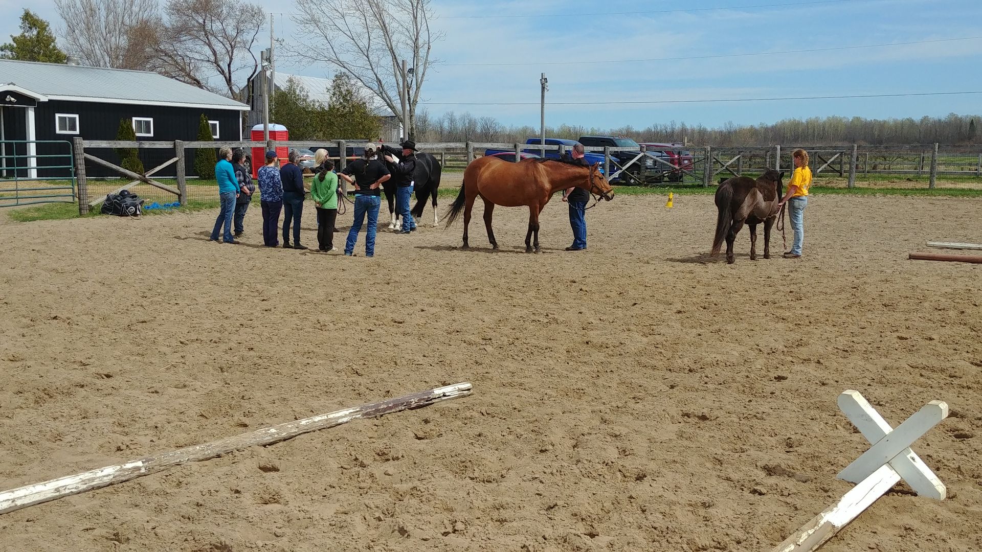 A group of people standing next to horses in a dirt field