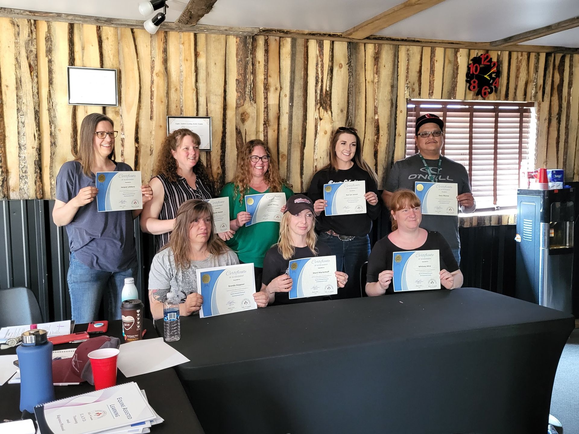 A group of people are standing around a table holding certificates.