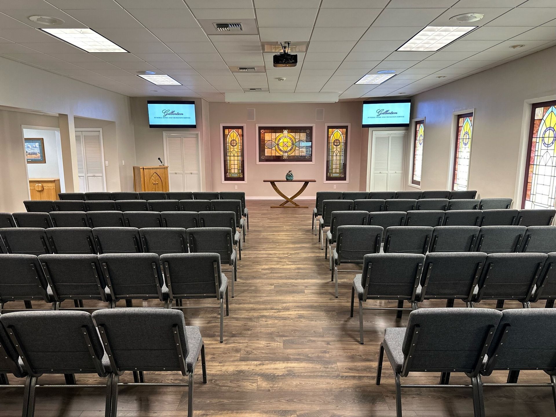 Rows of gray chairs face a small stage in a light-filled chapel.