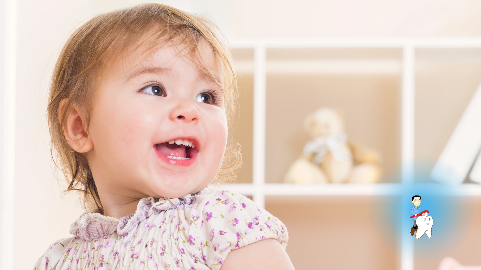 A little girl is sitting in front of a shelf and smiling.