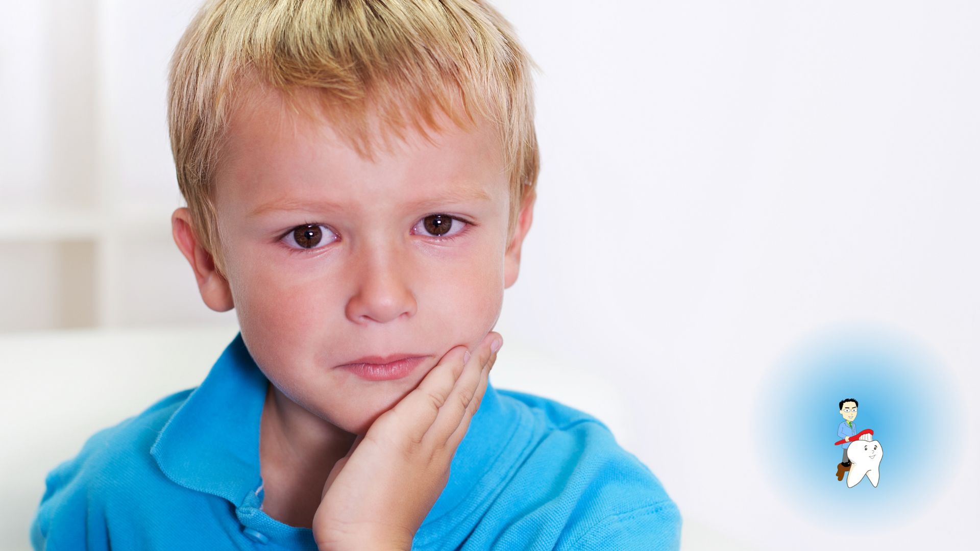 A young boy with a toothache is holding his hand to his face.