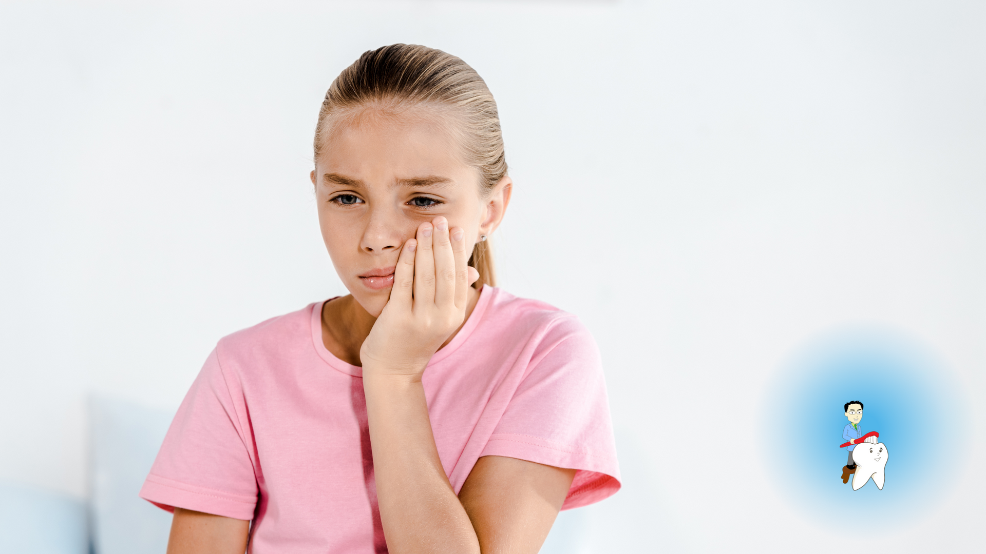 A young girl in a pink shirt is covering her face with her hand.