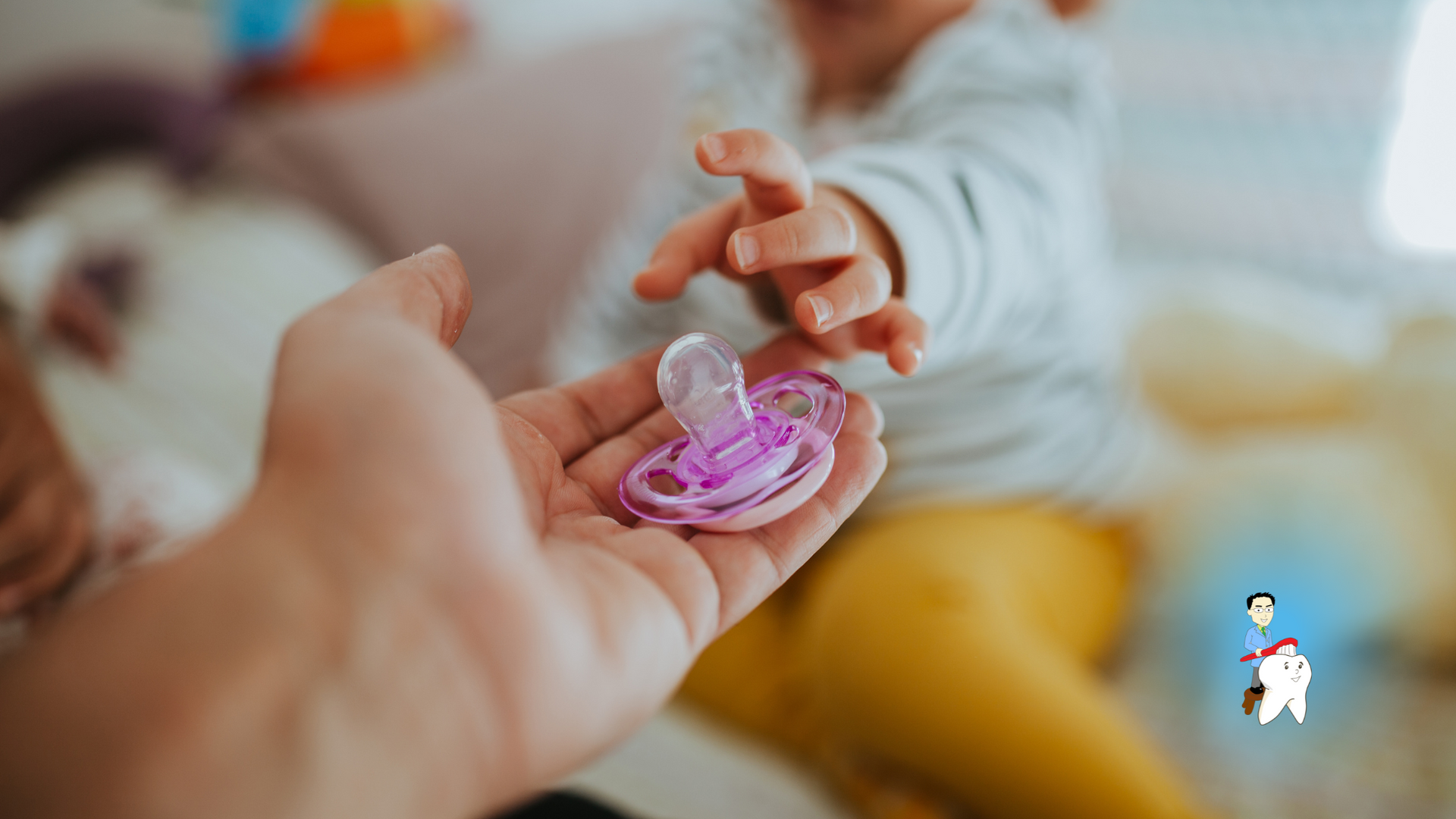 A baby is reaching for a pacifier in a person 's hand.