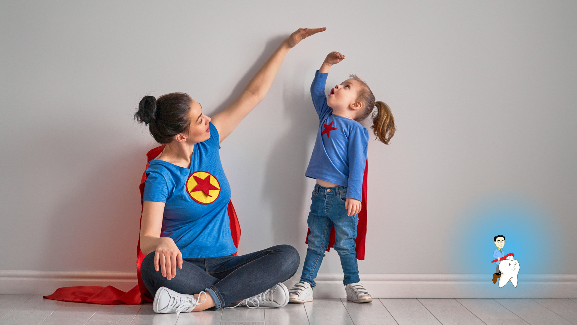 A woman and a little girl in superhero costumes are measuring their height against a wall.