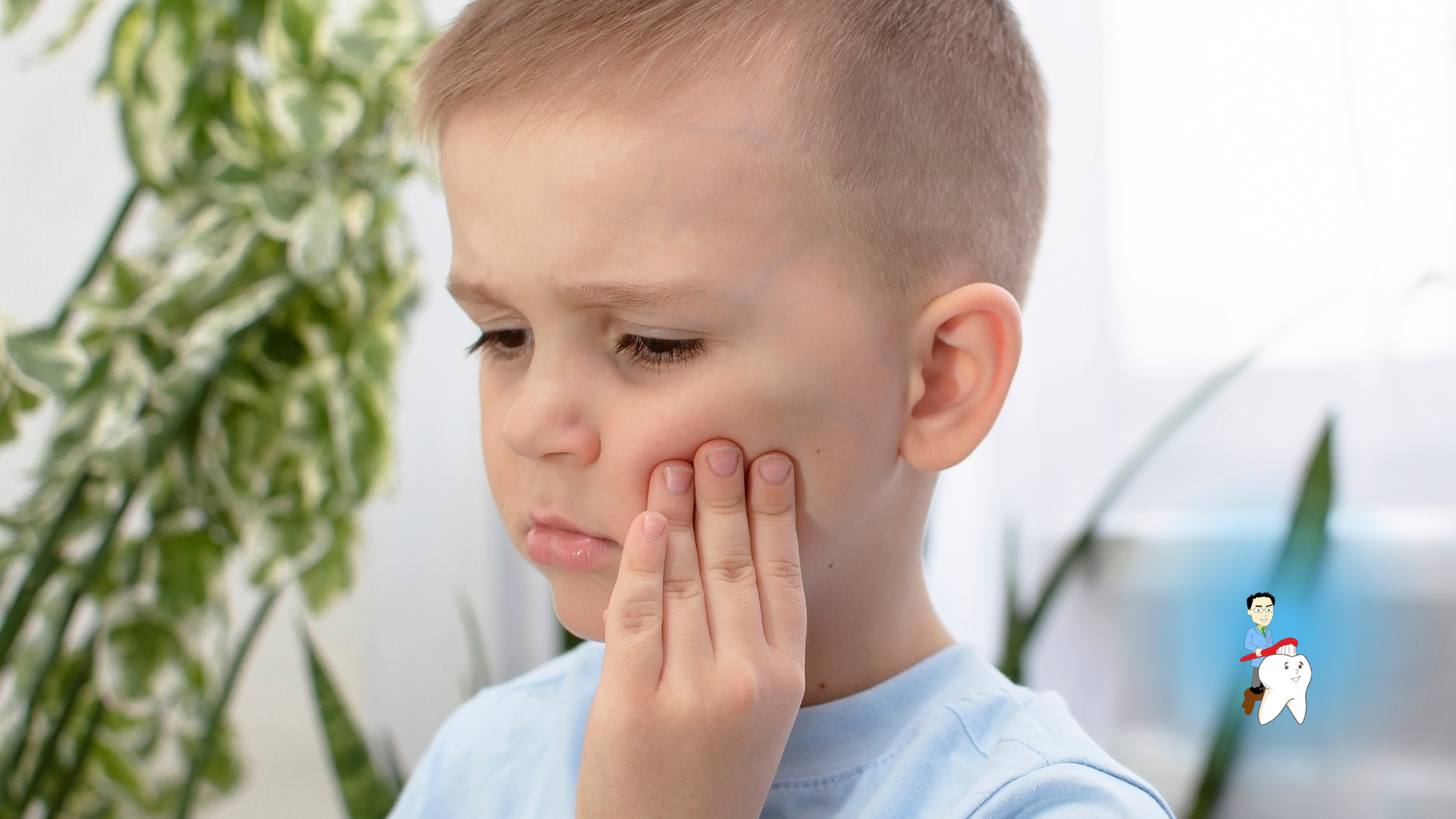 A young boy is holding his face in pain because of a toothache.