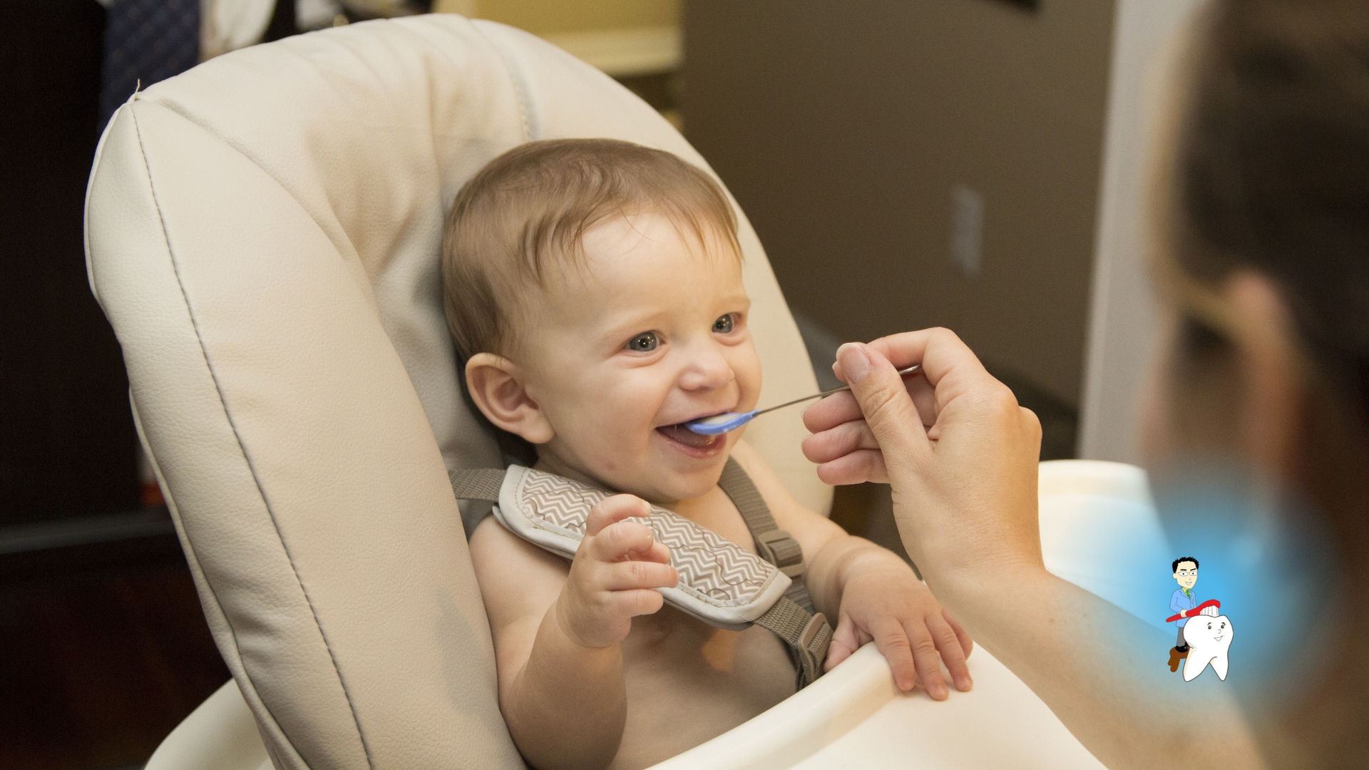 A woman is feeding a baby in a high chair with a spoon.