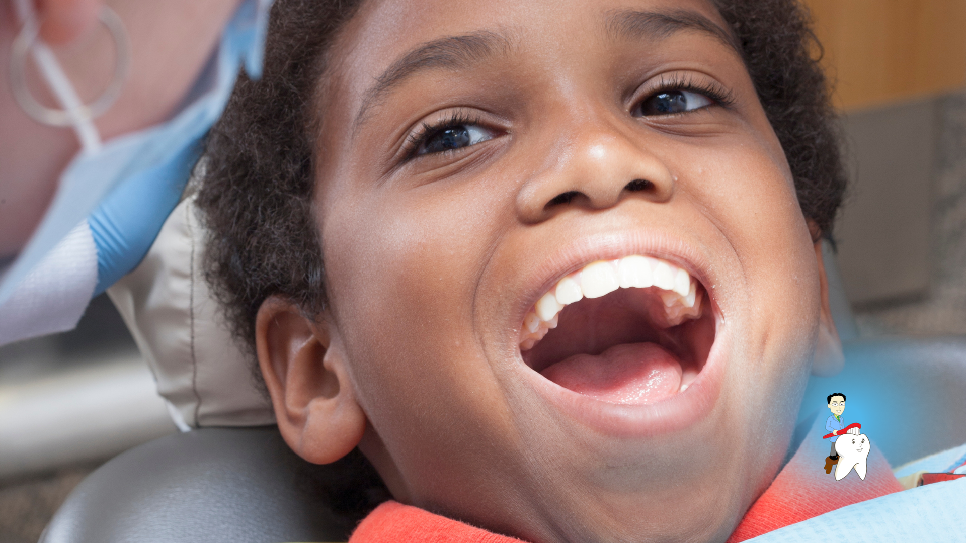 Child at the dentist with mouth open, dental tools visible, smiling.