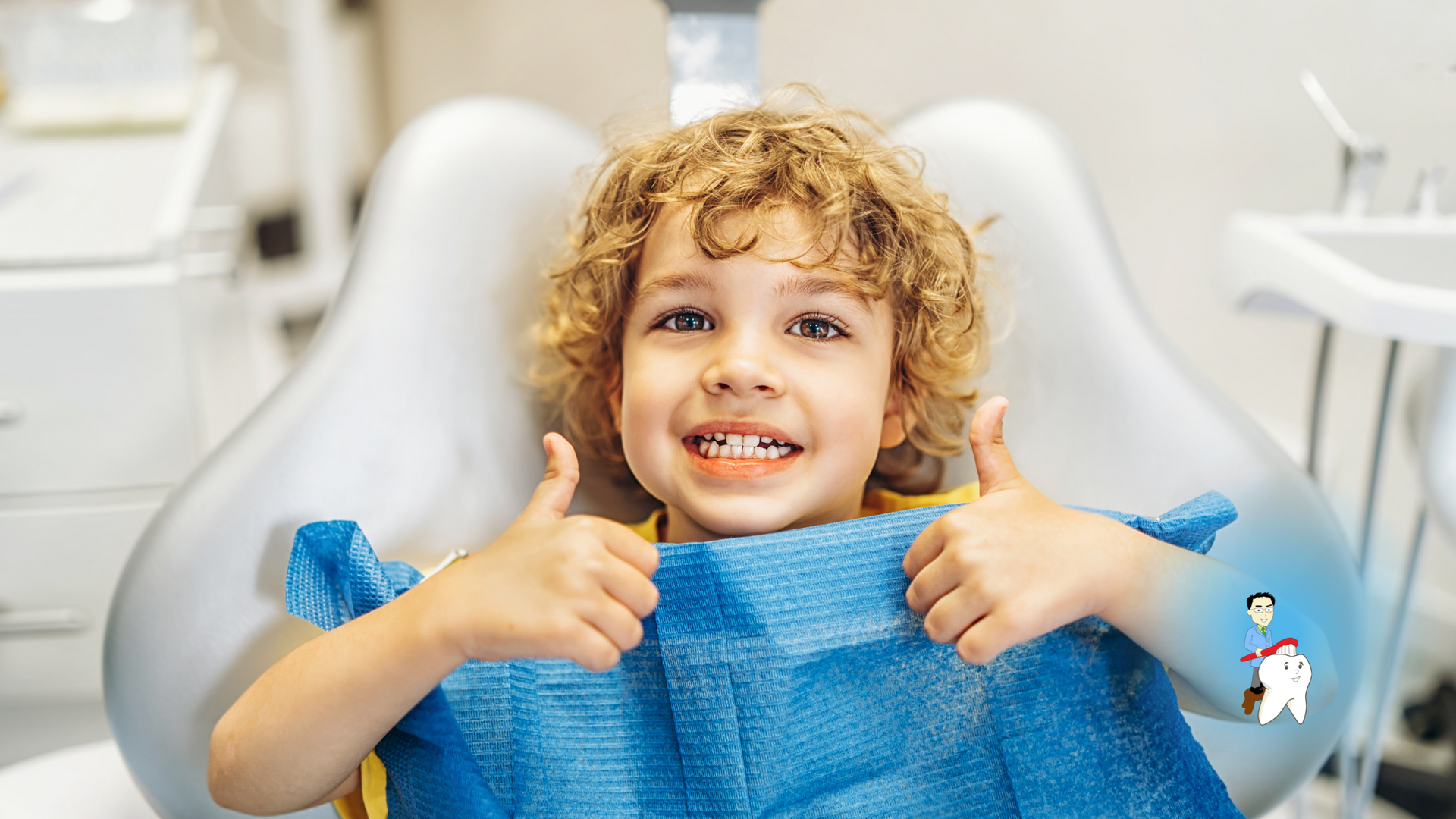 A young boy is sitting in a dental chair and giving a thumbs up.