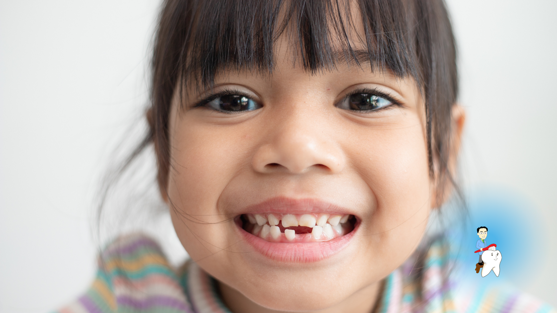 A little girl with missing teeth is smiling for the camera.