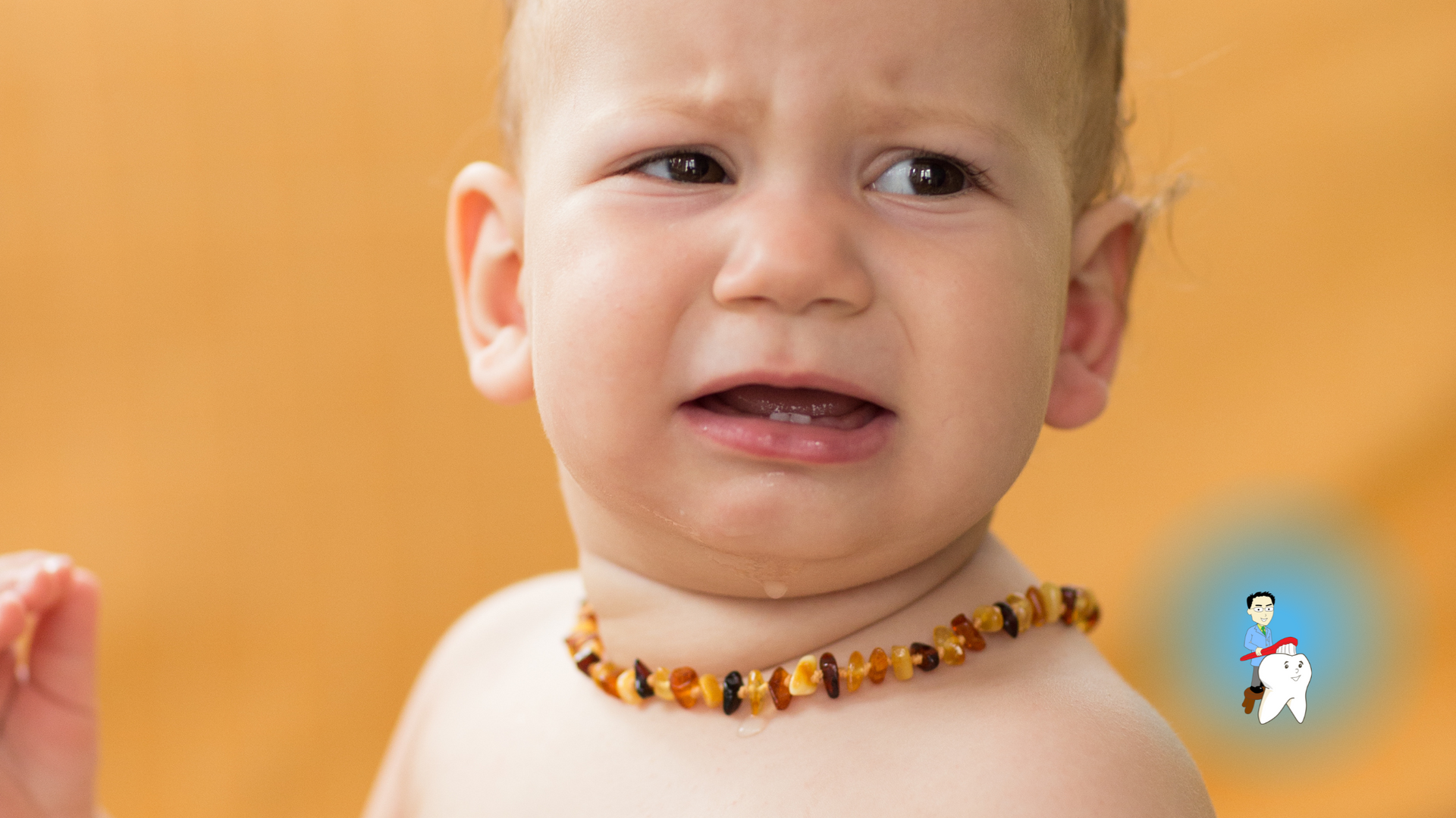 A baby wearing a necklace is crying.