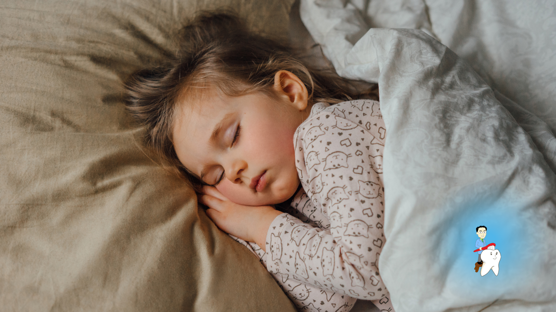 A little girl is sleeping on a bed under a blanket.