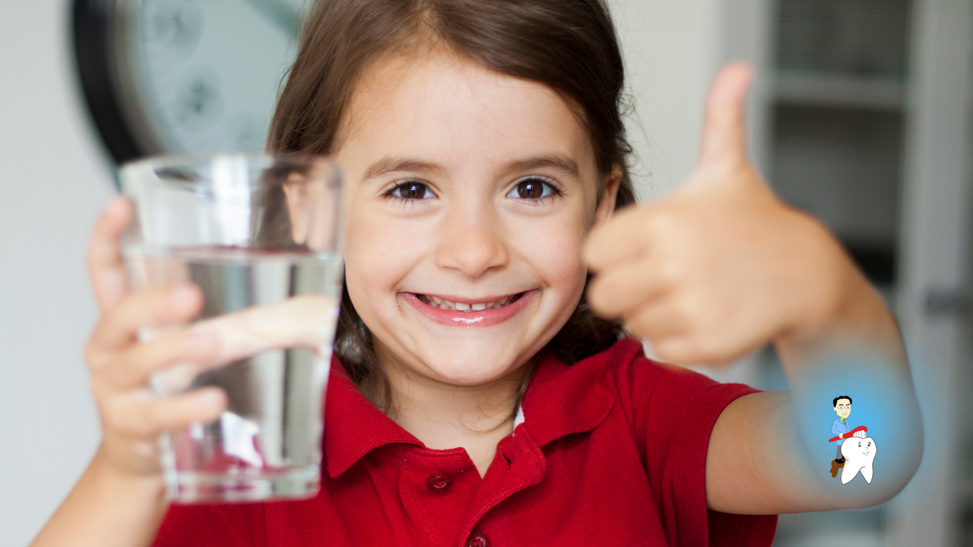 A little girl is holding a glass of water and giving a thumbs up.