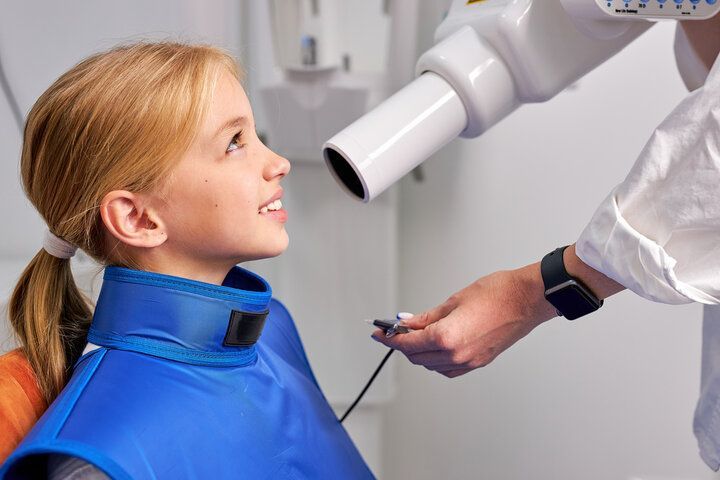 A little girl is getting an x-ray of her teeth at the dentist.