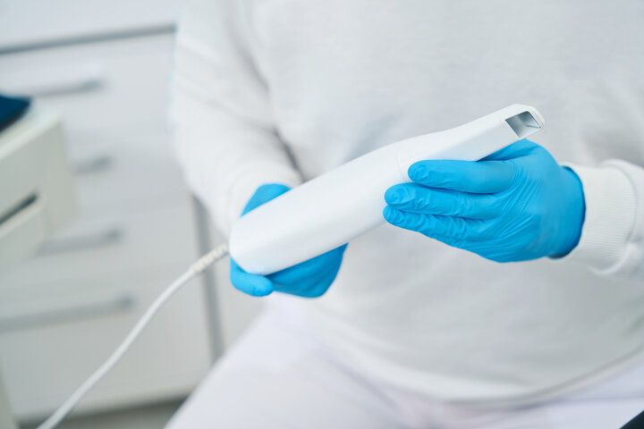 A person wearing blue gloves is holding a white object.