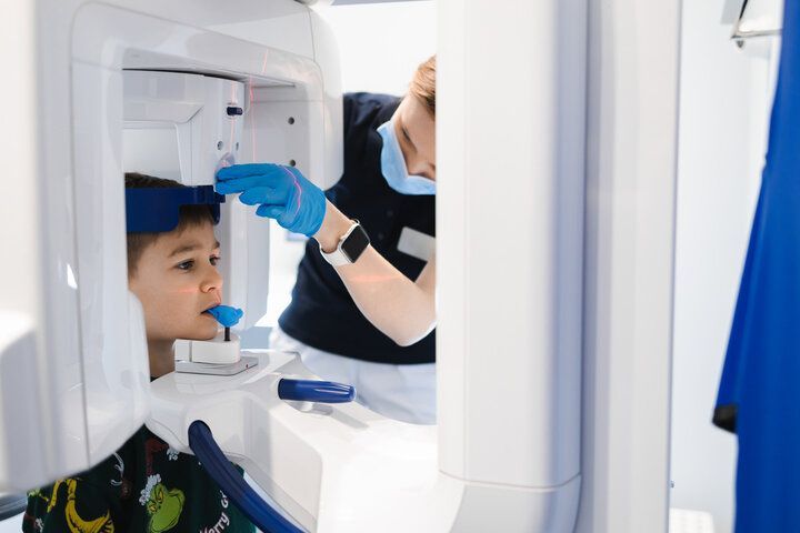 A young boy is getting an x-ray of his teeth by a dentist.