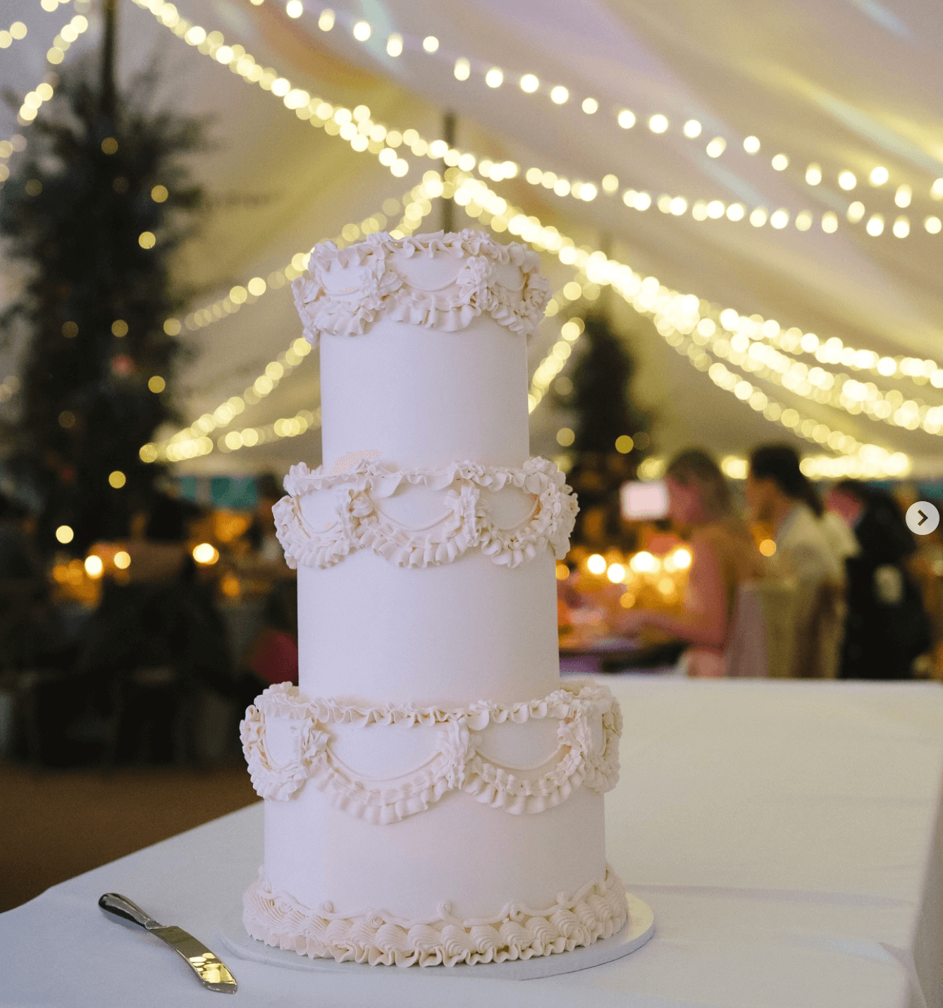 A white wedding cake is sitting on a white table