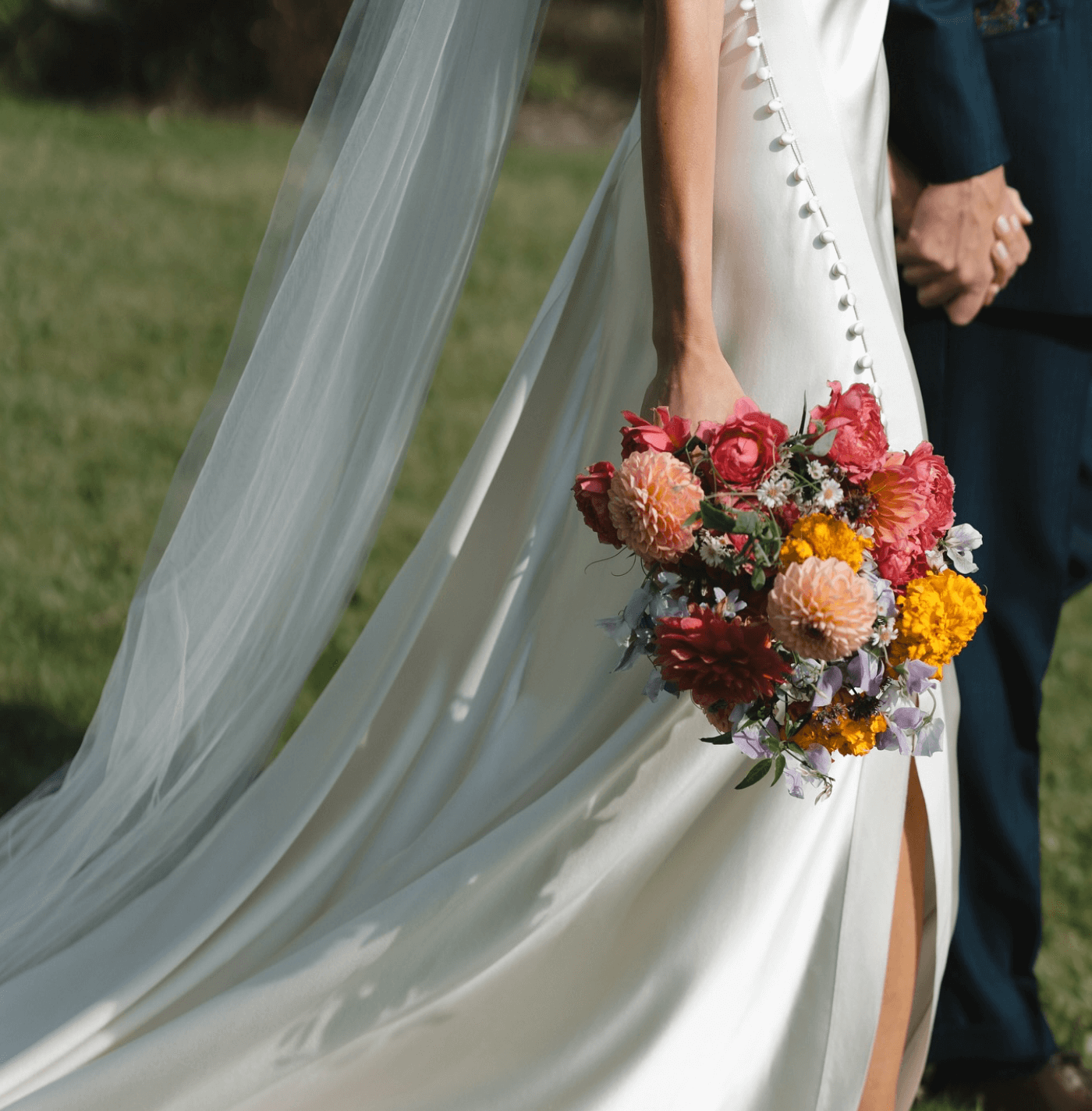 A bride in a white dress is holding a bouquet of flowers