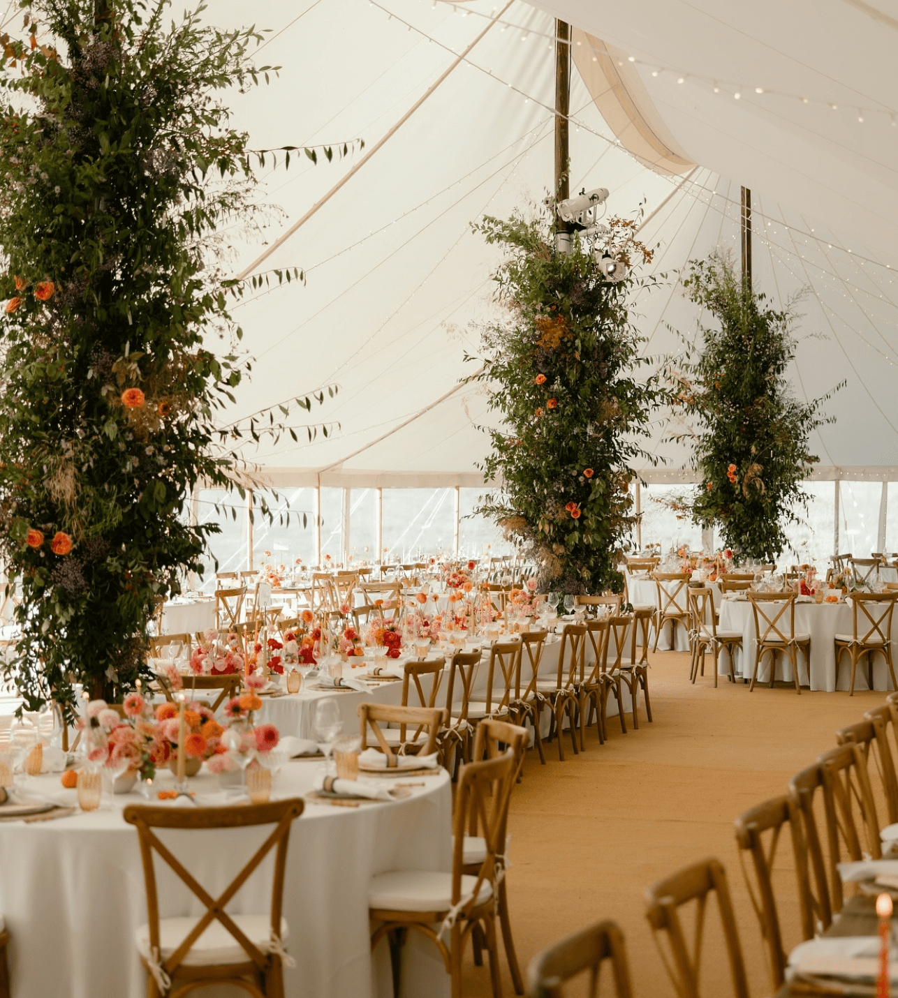 A large tent with tables and chairs set up for a wedding reception