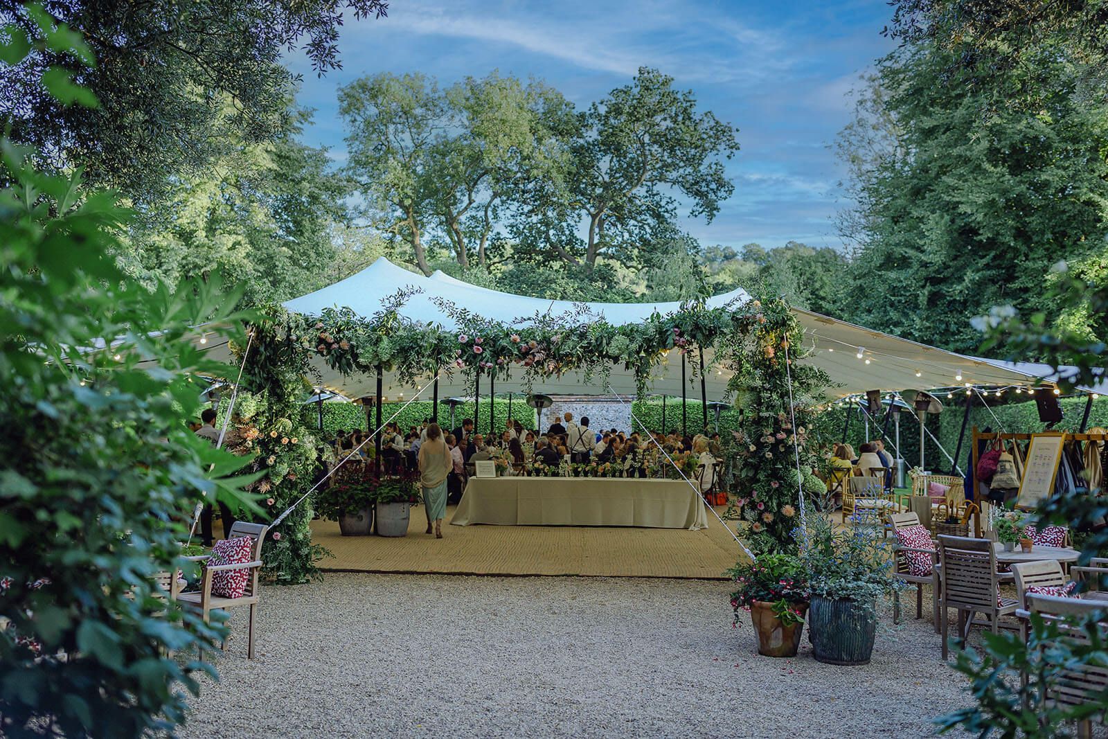 A group of people are gathered under a tent in a park.