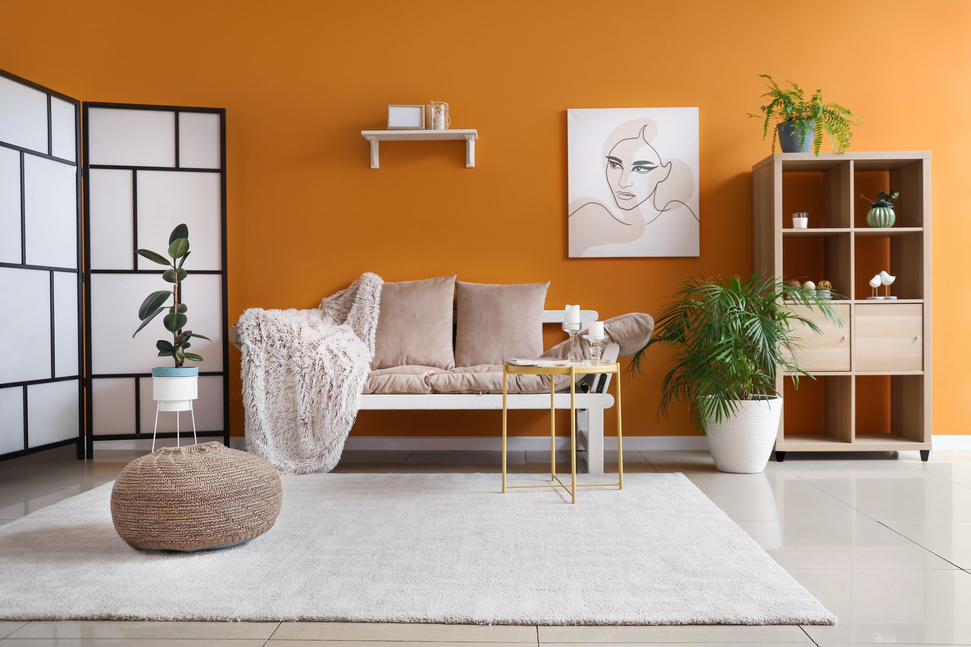 A living room with orange walls , a couch , a table and a rug.
