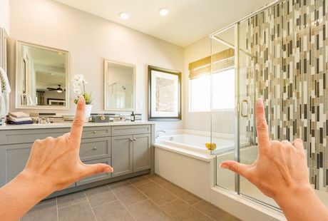 Picture of a remodeled bathroom with two hands forming the shape of a picture frame.