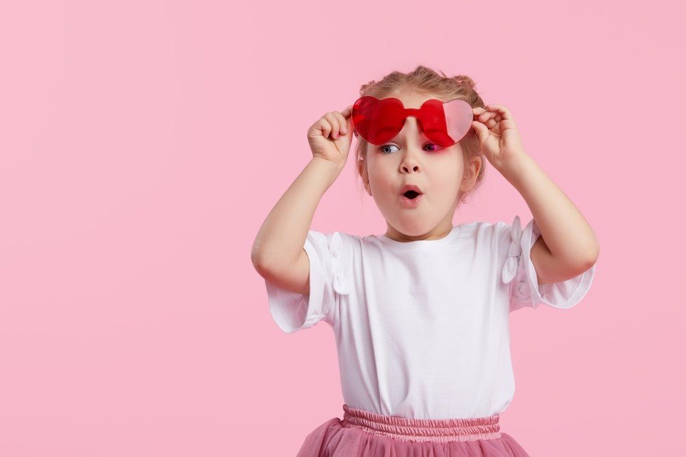 Bambina con occhiali rossi a forma di cuore