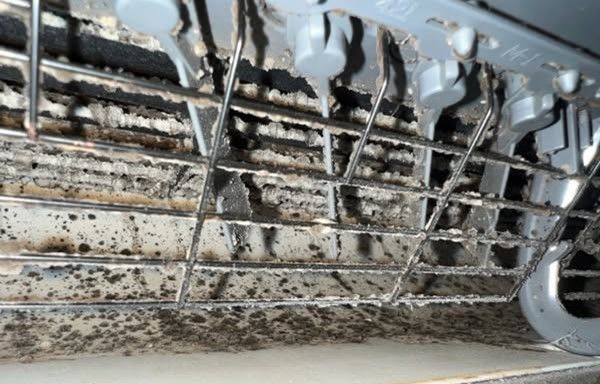 A close up of a dirty dishwasher with a lot of stains on it.