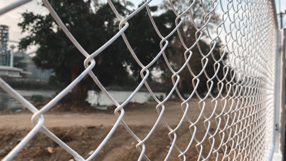 A Close Up of a Chain Link Fence With Trees in the Background — Brendan's Landscaping and Fencing In Bundaberg, QLD