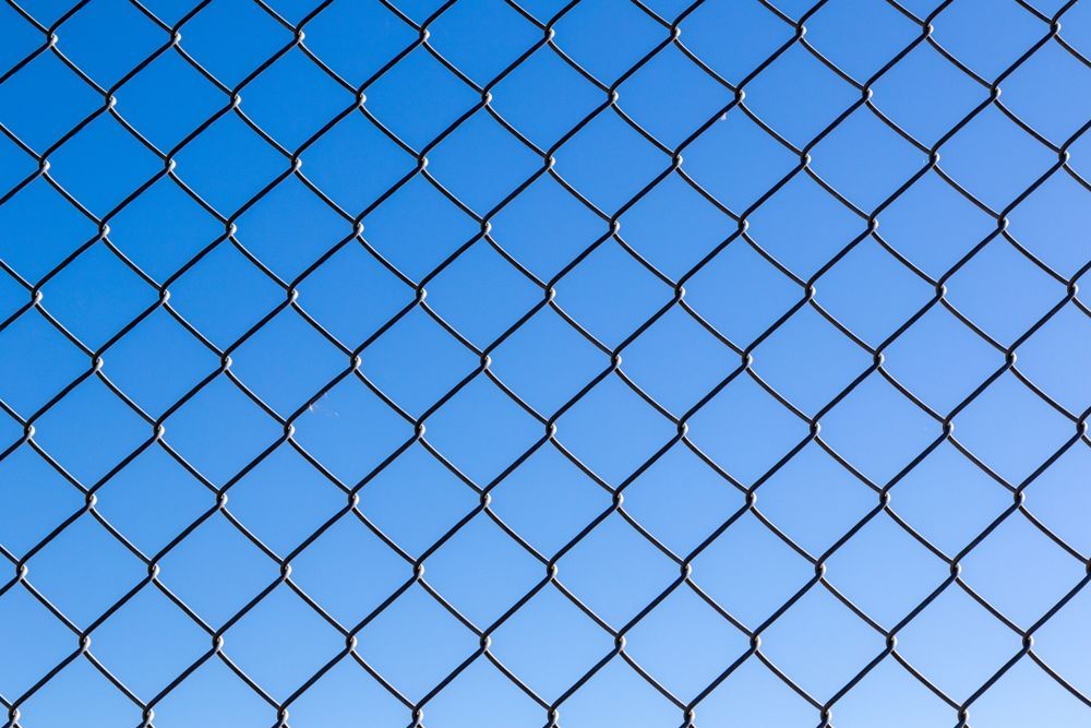 A Chain Link Fence is Against a Blue Sky — Brendan's Landscaping and Fencing In Bundaberg, QLD