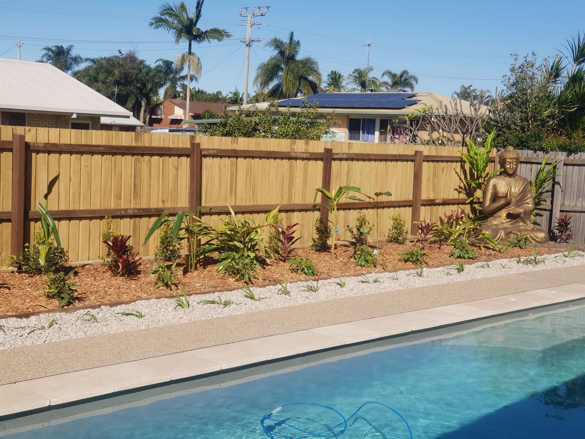 A Wooden Fence Surrounds a Swimming Pool in a Backyard — Brendan's Landscaping and Fencing In Bundaberg, QLD