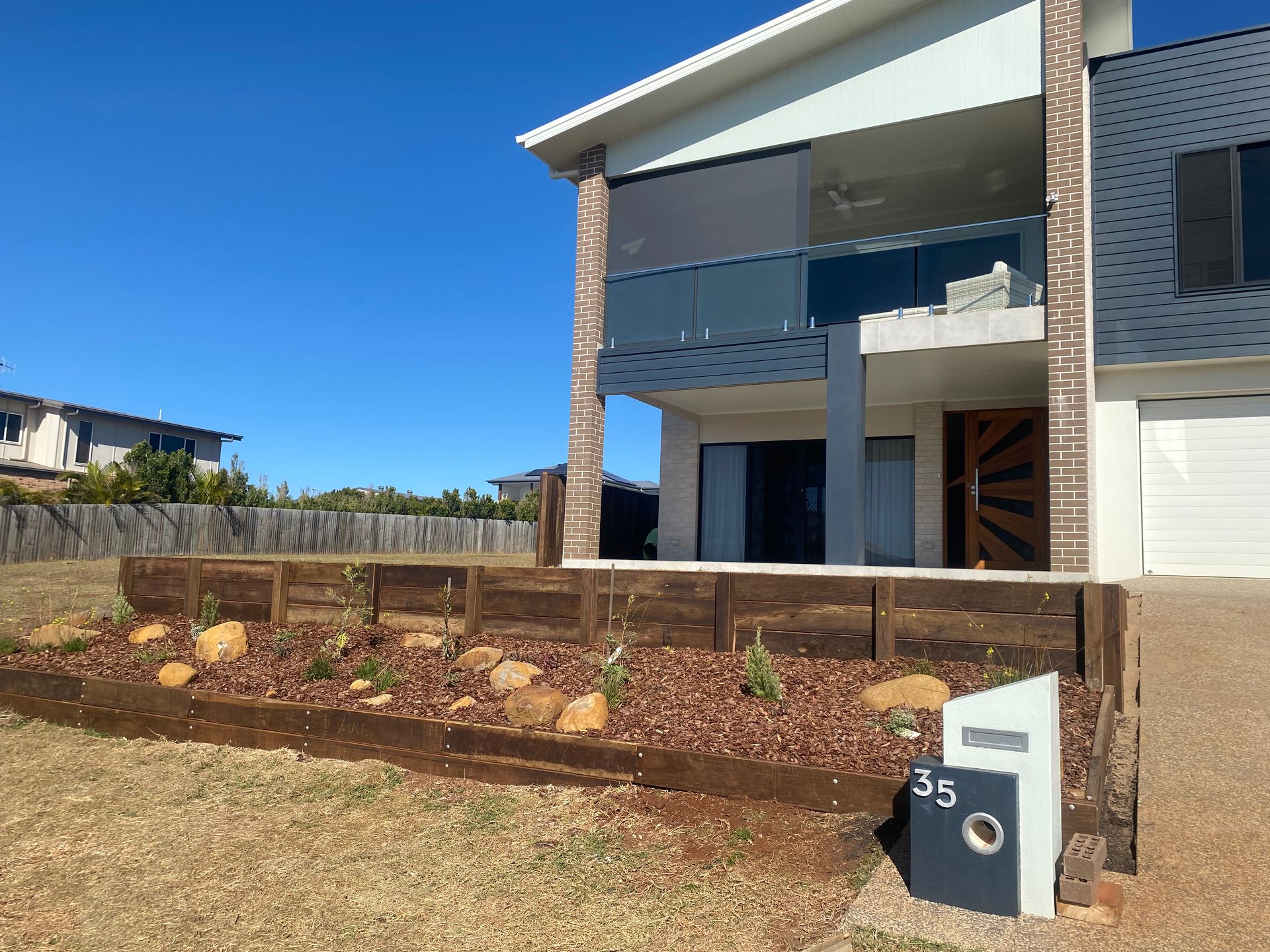 A Large Brick Wall With a Fence in the Background  — Brendan's Landscaping and Fencing In Bundaberg, QLD