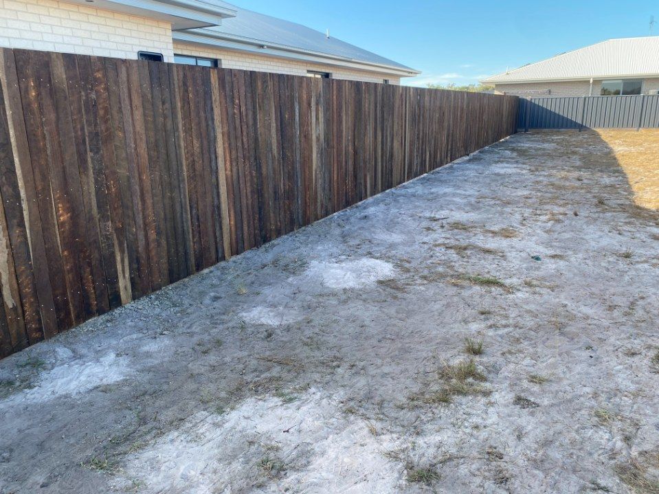 There is a Wooden Fence in the Backyard of a House — Brendan's Landscaping and Fencing In Moore Park Beach, QLD