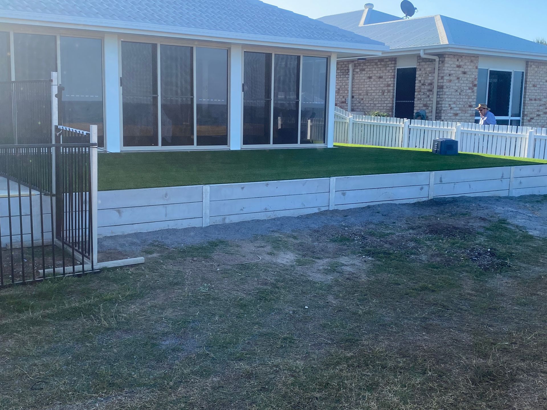 A Stone Wall With a Metal Fence Surrounding It — Brendan's Landscaping and Fencing In Bundaberg, QLD