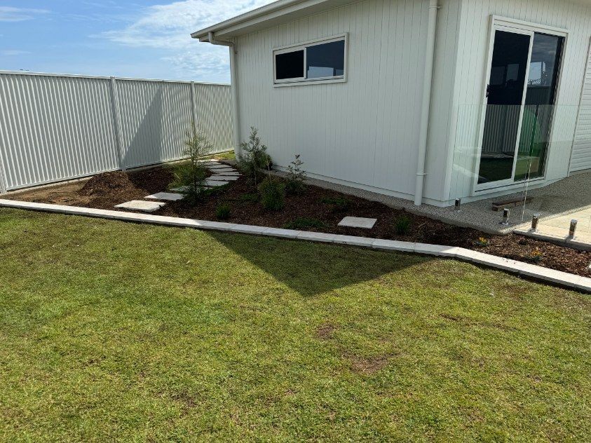 A White House With a Fence and a Lush Green Lawn in Front of It — Brendan's Landscaping and Fencing In Bundaberg, QLD