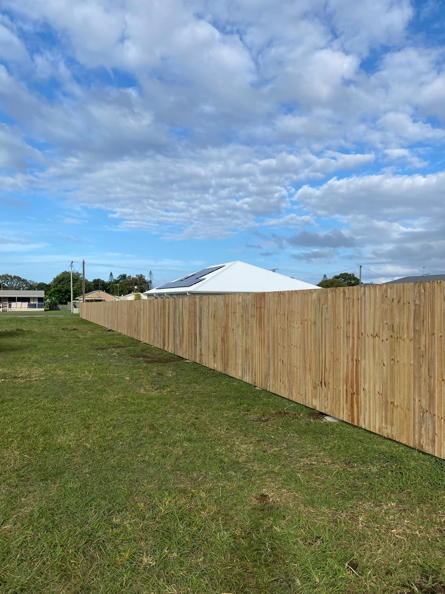 A Wooden Fence With a Sliding Gate in Front of a House — Brendan's Landscaping and Fencing In Bundaberg, QLD