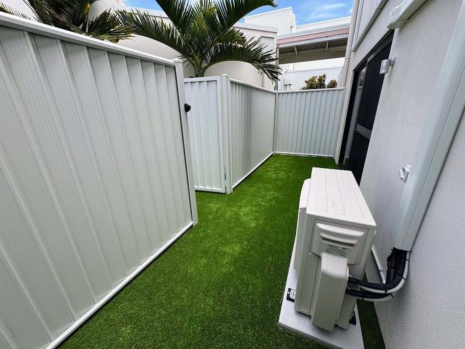 A Black Fence Surrounds a Lush Green Lawn — Brendan's Landscaping and Fencing In Bundaberg, QLD