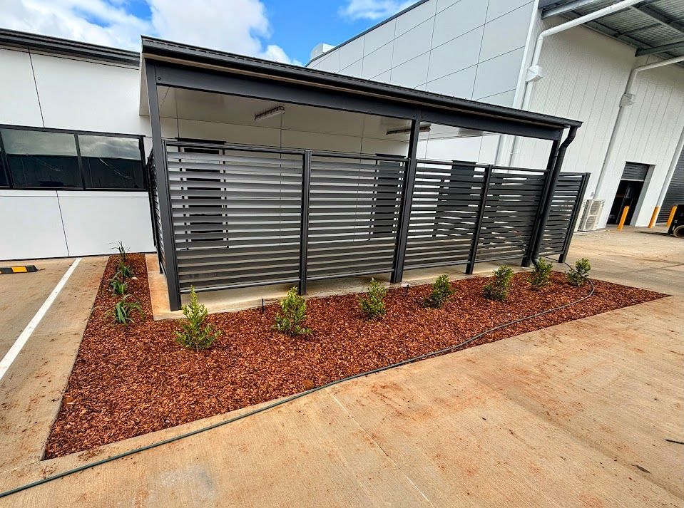 A Blue Shed With Purple Flowers in Front of It  — Brendan's Landscaping and Fencing In Bundaberg, QLD