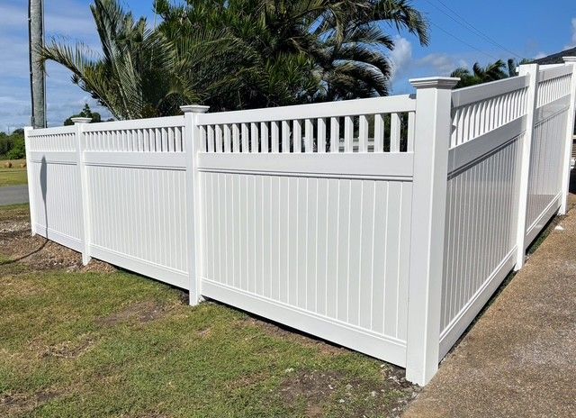 A White Lattice Fence is in Front of a Brick House — Brendan's Landscaping and Fencing In Bundaberg, QLD