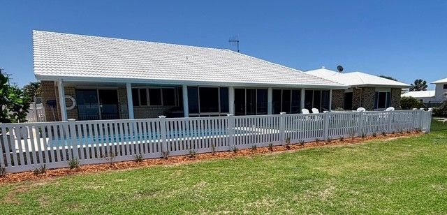 A Long White Picket Fence Surrounds a Grassy Field — Brendan's Landscaping and Fencing In Bundaberg, QLD