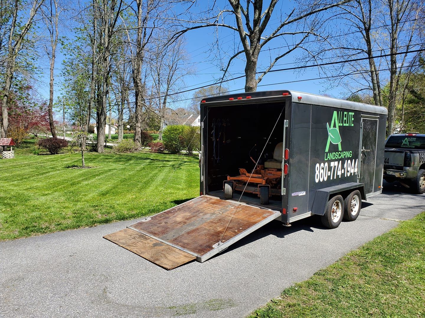 A trailer is parked on the side of the road with the ramp open.