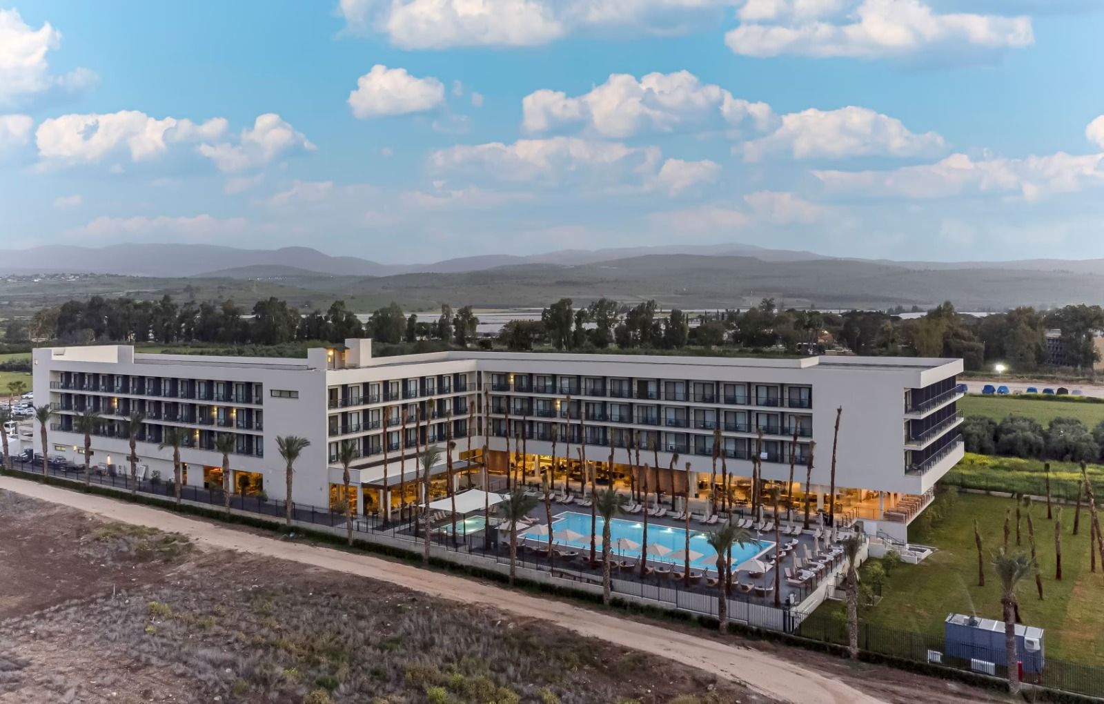מבט אווירי של בניין לבן גדול עם בריכת שחייה בחזיתו.