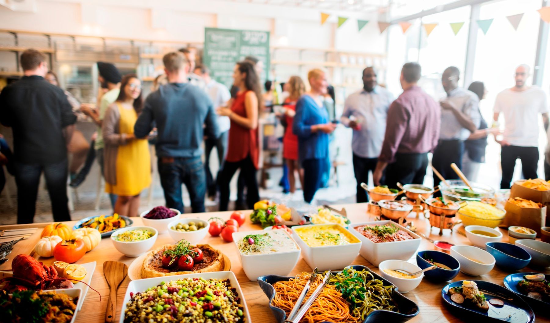 קבוצה של אנשים עומדת סביב שולחן מלא בהרבה אוכל.
