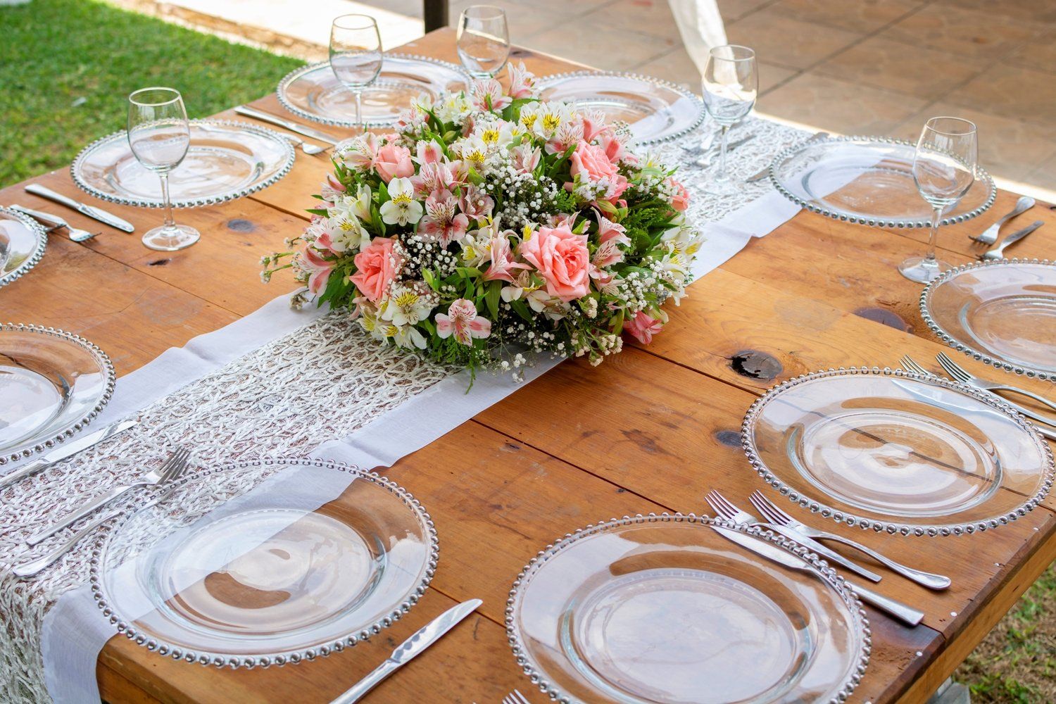 שולחן עץ ועליו צלחות , כלים ופרחים.