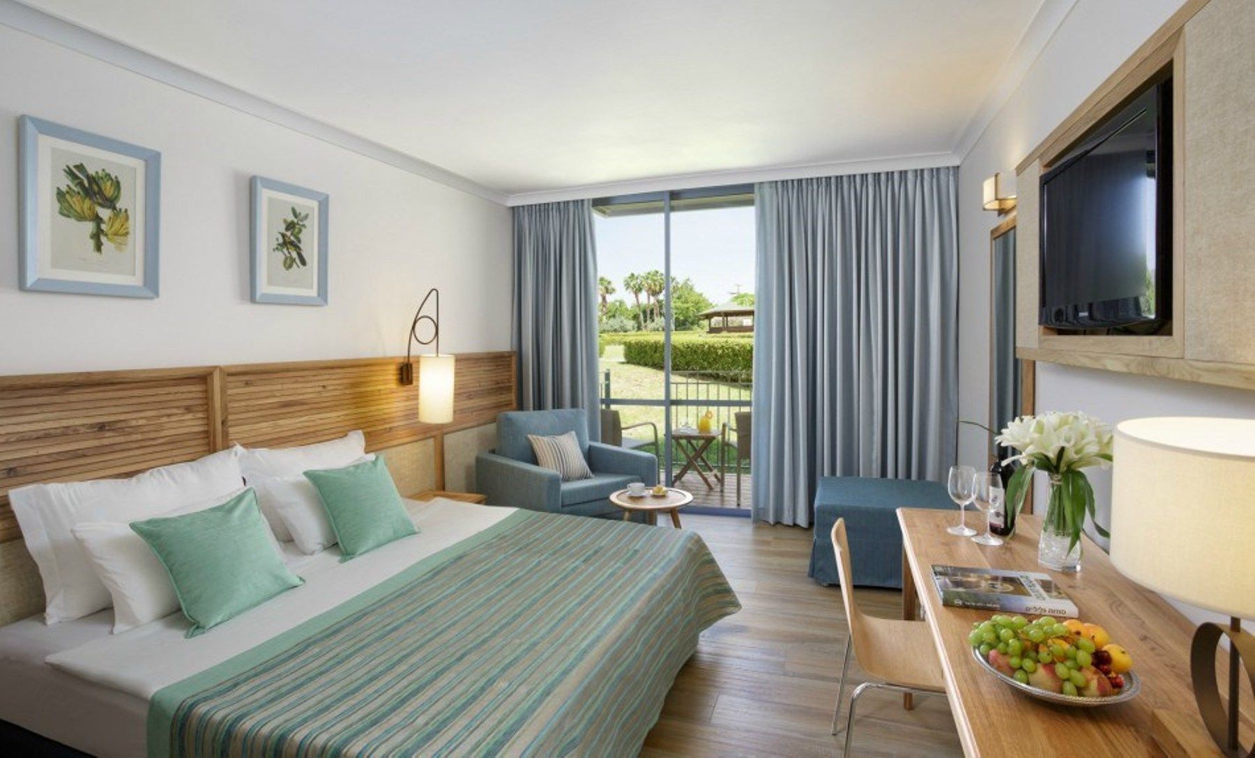 חדר מלון עם מיטת קינג סייז, שולחן עבודה, כיסא וטלוויזיה.