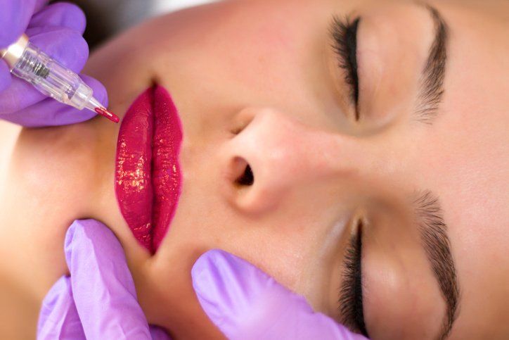 A woman is getting a permanent makeup tattoo on her lips.