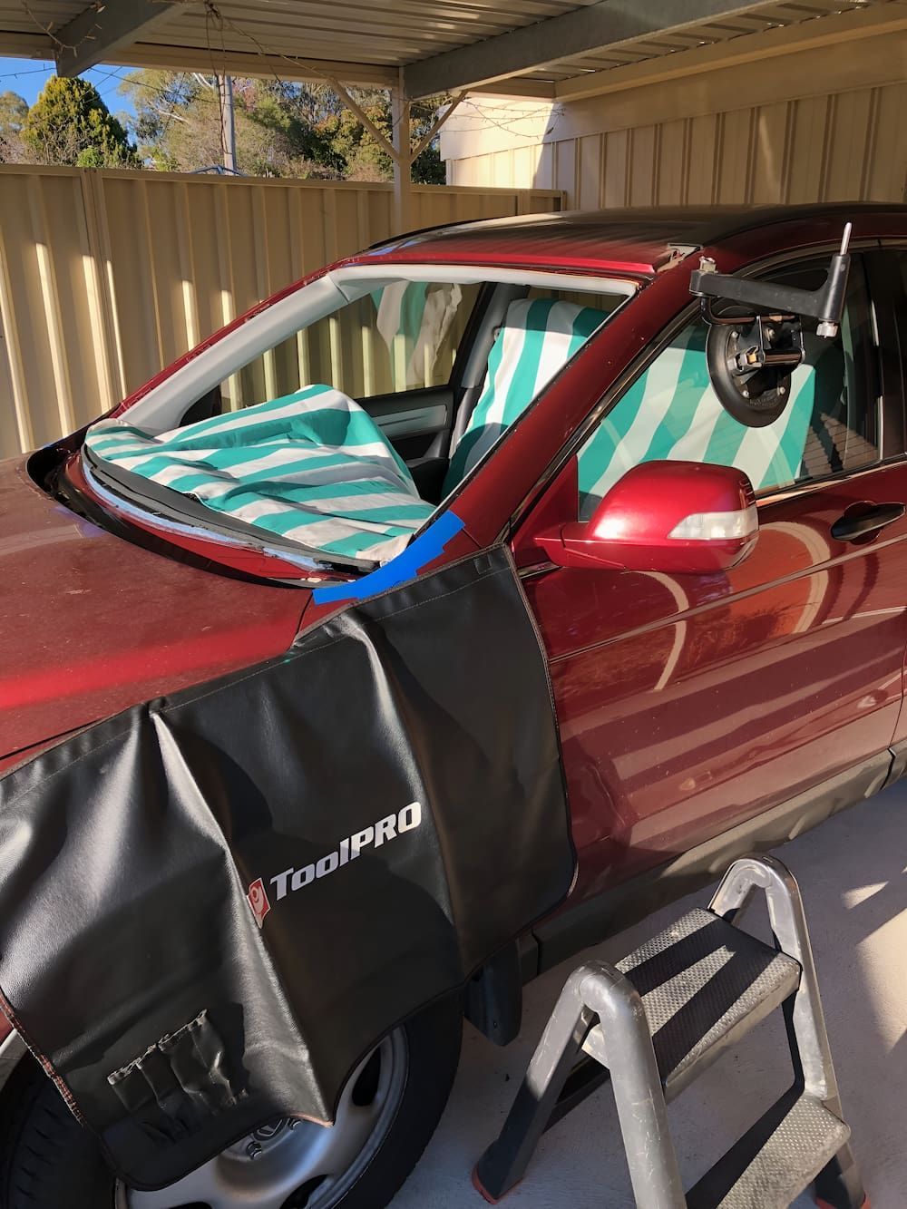A Red Car Is Parked In A Garage With A Towel On The Windshield — Canberra Windscreens In Gungahlin, ACT