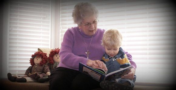 Elderly woman enjoys book with her grandson