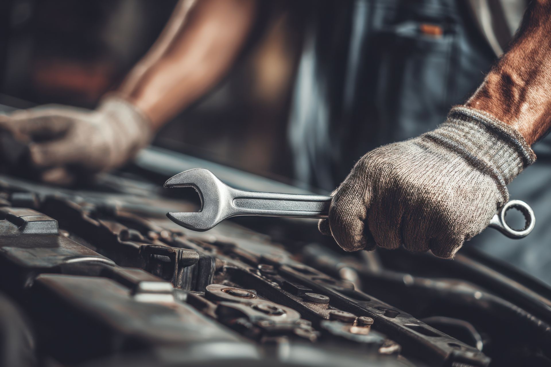 Mechanic working on a car transmission with gears and bearings visible on a metallic workbench