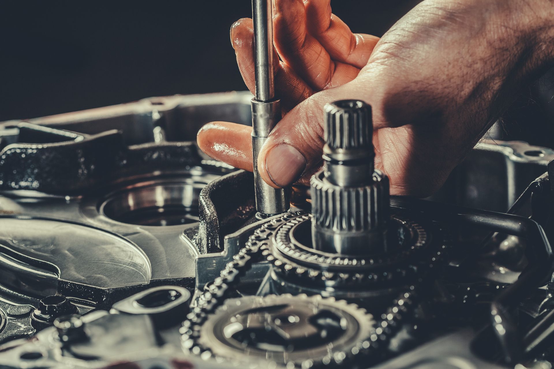 Close-up of a mechanic's hands repairing a gearbox in an auto transmission shop.