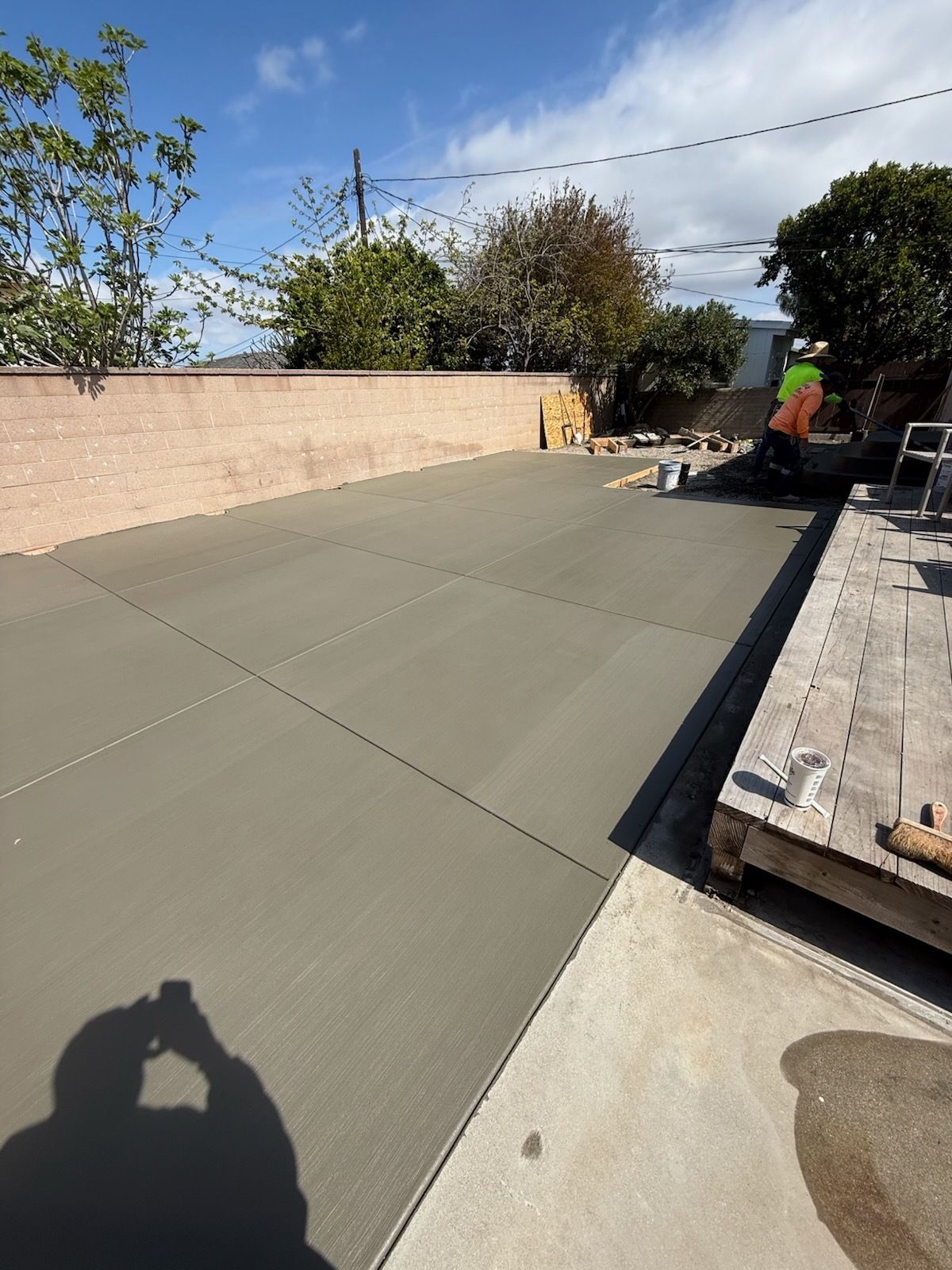 Newly poured concrete patio; worker in the background, sunny day.